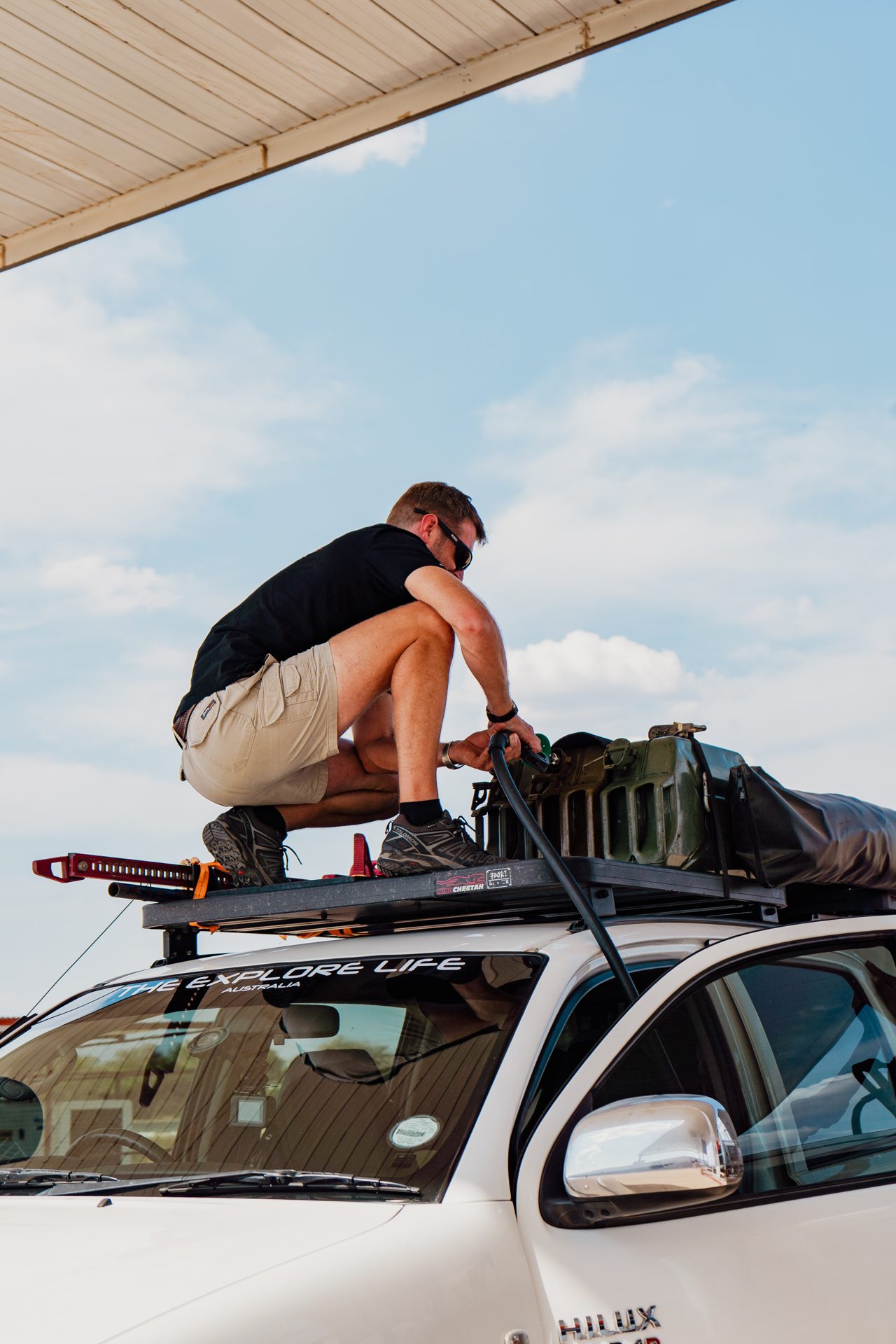 The Explore Life refilling jerry cans on the roof rack