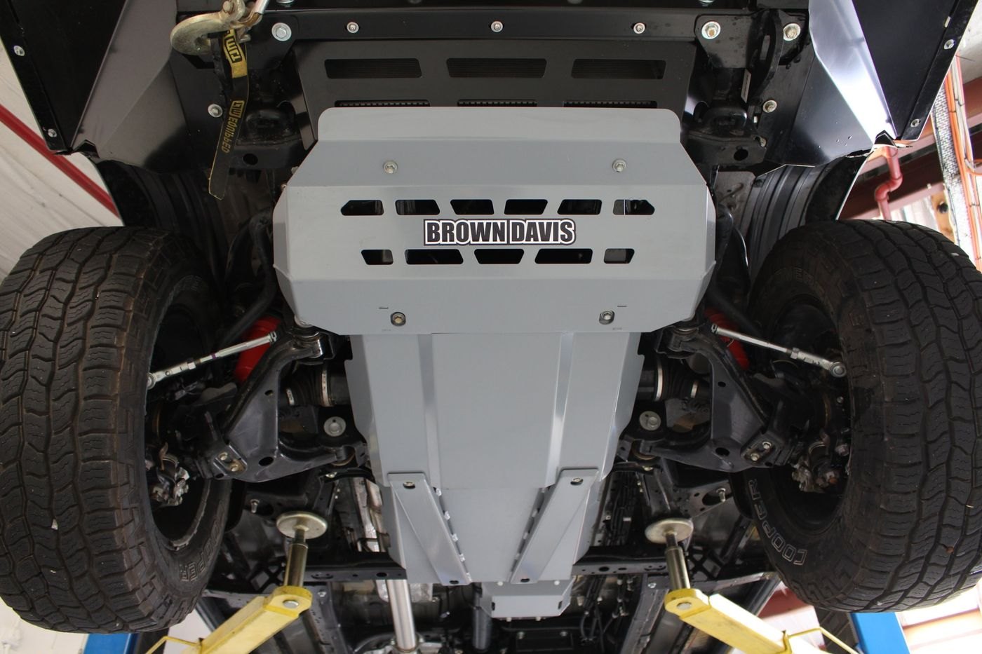 A full Brown Davis underguard set fitted under a 4WD, seen from below on a hoist